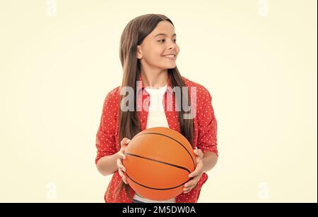 Ragazza teen con palla da basket isolata su sfondo bianco. Stile di vita sportivo e attivo. Infanzia, gioco di squadra. Ritratto di felice adolescente sorridente Foto Stock