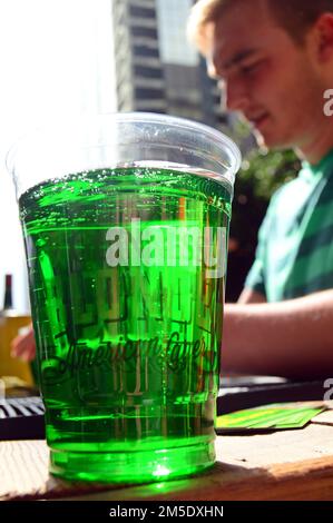 Un uomo adulto ordina un bicchiere di birra verde in un bar all'aperto il giorno di San Patrizio Foto Stock