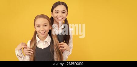 Scuole ragazze amici. I bambini della scuola felice con sguardo di bellezza portano i capelli lunghi in uniforme sfondo giallo formale. Ritratto di studentessa scolastica, studio Foto Stock