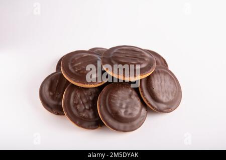 Foto di molti biscotti rotondi ricoperti di cioccolato in primo piano su sfondo bianco Foto Stock