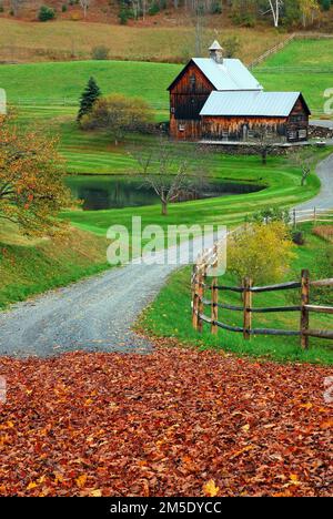 Una tortuosa strada di campagna conduce ad una fattoria bucolica in Vermont durante l'autunno del New England Foto Stock