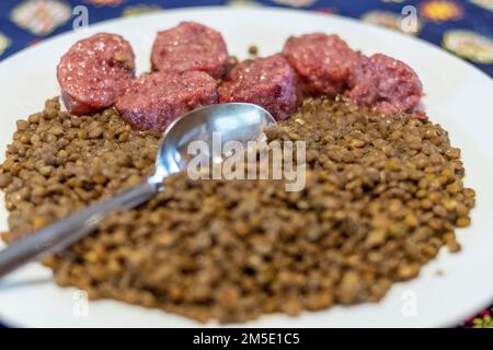 Le lenticchie e il cotechino sono il piatto principale del menu di Capodanno. Buon auspicio per i giorni a venire. Probabilmente originaria del Friuli-Venezia Giulia Foto Stock