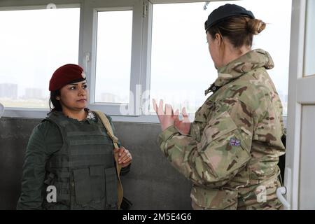 Una guardia di sicurezza di Peshmerga, una donna di Zerevani in servizio, ascolta un membro della Coalizione, insieme al gruppo di consiglieri militari - Nord, discutere l'importanza delle loro operazioni di sicurezza a Erbil, Iraq, 6 marzo 2022. Attraverso la congiunta Task Force – operazione inerente alla risoluzione, la Coalizione opera in stretta collaborazione con il governo iracheno e le forze partner di cui è stato veto nella Siria nord-orientale, con l’intento internazionale di garantire la sconfitta duratura di Daesh e di consentire la creazione di un quadro di cooperazione alla sicurezza duraturo. Foto Stock