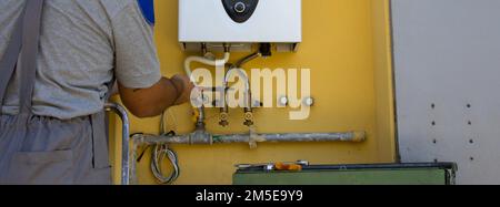 Immagine di un idraulico in lavoro che ripara e installa una caldaia a gas. Striscioni orizzontali Foto Stock
