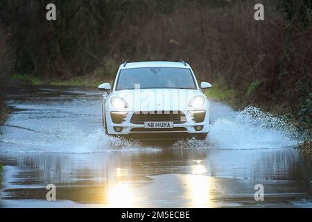 Muckleford, Dorset, Regno Unito. 28th dicembre 2022. Meteo nel Regno Unito. Un'auto passa attraverso le acque alluvionali su una strada a Muckleford vicino a Dorchester a Dorset dopo una giornata di forte pioggia e forti venti polverosi. Picture Credit: Graham Hunt/Alamy Live News Foto Stock