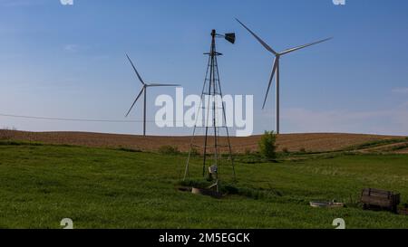 Una struttura in acciaio sul campo erboso prima delle turbine eoliche con sfondo cielo blu Foto Stock