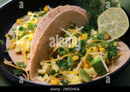 primo piano della colazione con tortilla al keto con uova strapazzate, avocado, formaggio e coriandolo Foto Stock