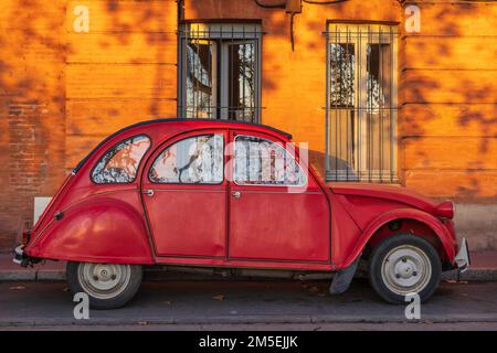 Tolosa, Francia - 12 21 2022 : Vista di rosso brillante iconica Citroen 2CV auto aka brutto anatroccolo, Dolly o lumaca stagno, parcheggiato in una strada Foto Stock