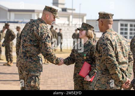 STATI UNITI Charlotte Marchek, un tecnico di impianti mobili con Marine Aviation Logistics Squadron (MALS) 12, a destra, scuote le mani con il Lt. Michael Lupient, comandante di MALS-12, presso Marine Corps Air Station Iwakuni, Giappone, 8 marzo 2022. Marchek ha ricevuto la Medaglia Navy and Marine Corps Achievement per essere stato il 1st Marine Aircraft Wing Marine dell'anno. Marine of the Year viene assegnata a Marines che dimostrano leadership e coraggio nel corso del loro servizio, offrono un sostegno eccezionale con chi servono, migliorano il morale e, attraverso la loro guida, ispirano Foto Stock