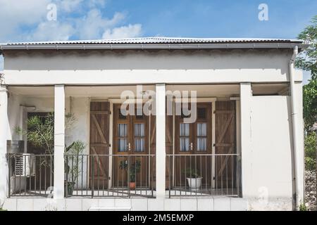 Facciata di una casa retrò parete bianca con due porte in legno e cancello all'ingresso Foto Stock