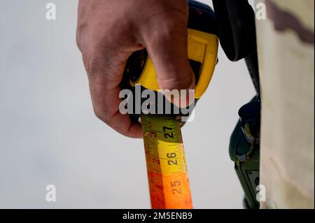 Un Airman assegnato allo Squadron, ingegnere civile del 8th, afferra una misura a nastro mentre si prepara a valutare la profondità di un buco svuotato durante il corso di Rapid Airfield Damage Repair presso la base aerea di Kunsan, Repubblica di Corea, 9 marzo 2022. RADR è un processo in più fasi per la riparazione rapida delle superfici del campo d'aria. Foto Stock