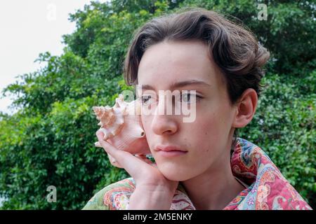 Teen caucasico che tiene una conchiglia gigante Foto Stock