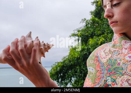 Teen caucasico che tiene una conchiglia gigante Foto Stock