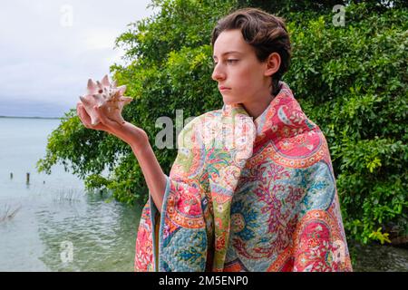 Teen caucasico che tiene una conchiglia gigante Foto Stock