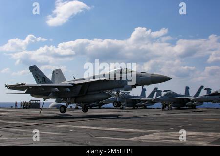 MARE DELLE FILIPPINE (10 marzo 2022) un F/A-18E Super Hornet, assegnato ai 'Tophatters' di Strike Fighter Squadron (VFA) 14, si prepara a fare un atterraggio arrestato sul ponte di volo della portaerei di classe Nimitz USS Abraham Lincoln (CVN 72). Abraham Lincoln Strike Group è in fase di implementazione pianificata nell'area delle operazioni della flotta 7th degli Stati Uniti per migliorare l'interoperabilità attraverso alleanze e partnership e al tempo stesso fungere da forza di risposta pronta a sostegno di una regione indomPacifico libera e aperta. Foto Stock
