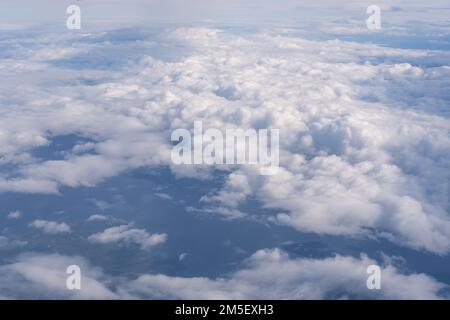 La vista dalla finestra piana alle nuvole e al suolo. Il paesaggio della superficie terrestre, visibile da un aeroplano sotto nuvole bianche e blu Foto Stock