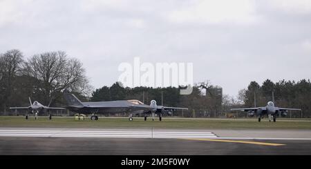 Un F-35A Lightning II assegnato al 495th Fighter Squadron taxi per la pista di fronte a F-15E Strike Eagles dal 494th Fighter Squadron a Royal Air Force Lakenheath, Inghilterra 9 marzo 2022. La formazione di routine consente ai piloti di essere pronti per le minacce attuali ed emergenti in un teatro in continua evoluzione. Foto Stock