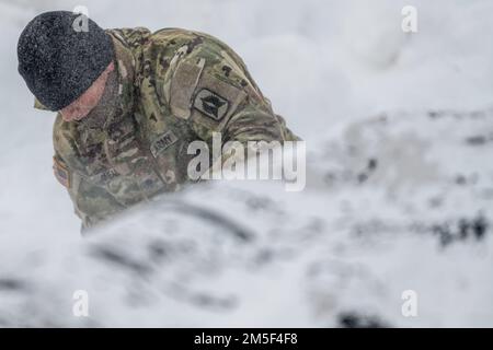 STATI UNITI Lo specialista dell'esercito Michael Oneal, un membro dell'equipaggio di Avenger assegnato a 1st battaglione, 265th Air Defense Artillery Regiment, Florida Army National Guard, prepara un tarpo camuffato da posizionare su un sistema di difesa aerea Avenger durante l'esercitazione ARCTIC EDGE 2022 presso la base aeronautica di Eielson, Alaska, 10 marzo 2022. Il sistema di difesa aerea Avenger è un sistema di missili superficie-aria semovente che fornisce una protezione aerea mobile a corto raggio per le unità a terra contro missili da crociera, veicoli aerei senza equipaggio, aerei ad ala fissa a basso volo ed elicotteri. AE22 è una patria biennale de Foto Stock