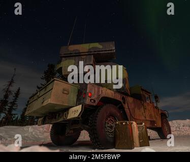 Le luci del nord si illuminano sopra un sistema di difesa aerea del Avenger assegnato a 1st battaglione, 265th reggimento dell'artiglieria di difesa dell'aria, la guardia nazionale dell'esercito della Florida, durante l'esercitazione DEL BORDO ARTICO 2022 alla base dell'aeronautica di Eielson, Alaska, 11 marzo 2022. Il sistema di difesa aerea Avenger è un sistema di missili superficie-aria semovente che fornisce una protezione aerea mobile a corto raggio per le unità a terra contro missili da crociera, veicoli aerei senza equipaggio, aerei ad ala fissa a basso volo ed elicotteri. Foto Stock