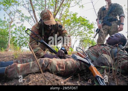 NEGLI STATI UNITI Esercito Verde Beret assegnato a forze speciali distacco operativo Alpha (SFOD-A) 3212, Una società, 2nd Battaglione, 3rd Gruppo forze speciali (Airborne) osserva come un soldato Beninese applica un tourniquet al suo compagno di squadra durante Joint Combined Exchange Training (JCET) a Ouassa, Africa, 11 marzo 2022. Il coinvolgimento degli Stati Uniti ha un vantaggio reciproco, sostiene le norme internazionali e tratta i partner come uguali. Foto Stock