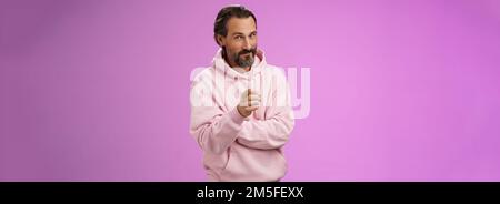 Uomo carismatico e carismatico in elegante felpa con cappuccio rosa invitandoli ad unirsi all'azienda sorridente auto-assicurato indicando che il selezionamento fa Foto Stock