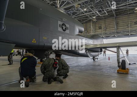 Il personale della forza di autodifesa aerea giapponese guarda un falco globale RQ-4B in un hangar della base aerea di Misawa, Giappone, 12 marzo 2022. Il modello RQ-4B è un aeromobile pilotato in remoto ad alta quota, lunga durata e con una suite di sensori integrati che offre funzionalità globali per tutte le condizioni atmosferiche, di intelligence diurna o notturna, sorveglianza e ricognizione. L'aggiunta di questo aeromobile all'inventario della Japan Air Self-Defense Force sostiene direttamente la difesa del Giappone e la pace e la stabilità nella regione dell'Indo-Pacifico. Foto Stock