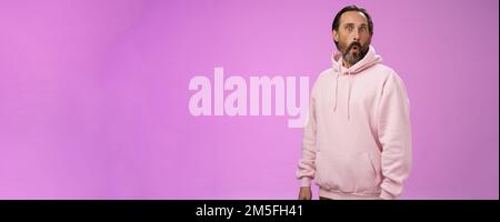 Impressionato speechless scioccato adulto bearded uomo capelli grigi in fresco pink hoodie pieghevole labbra wow occhi schioccanti macchina fotografica sorpreso stupito incuriosito Foto Stock