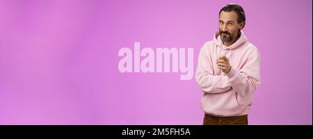 Uomo carismatico e carismatico in elegante felpa con cappuccio rosa invitandoli ad unirsi all'azienda sorridente auto-assicurato indicando che il selezionamento fa Foto Stock
