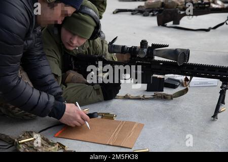 NEGLI STATI UNITI Special Operations Forces member with 10th Special Forces Group spiega il proprio obiettivo di avvistare un membro delle forze di Volontariato di difesa nazionale lituane (KASP) su una serie vicino a Kaunas, Lituania 12 marzo 2022. Queste valutazioni congiunte della gamma giornaliera sono utilizzate per scambiare tattiche, migliorare la preparazione alle missioni e mantenere avanzate abilità di marketing di combattimento, promuovendo al contempo una forte collaborazione con le forze alleate. Foto Stock