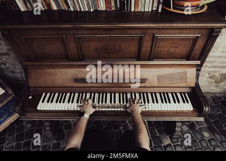Un uomo che suona un vecchio pianoforte. Foto Stock