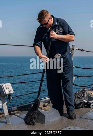 GOLFO ARABICO (16 marzo 2022) il compagno di Gunner Classe 1st Jeffery Watson spazza l’acqua fuori dal ponte missilistico a bordo del cacciatorpediniere missilistico guidato USS Gridley (DDG 101) durante un’evoluzione del lavaggio di acqua dolce nel Golfo Arabico, marzo 16. Gridley è schierato nell'area delle operazioni della flotta degli Stati Uniti 5th a sostegno delle operazioni navali per assicurare la stabilità e la sicurezza marittima nella regione centrale, collegando il Mediterraneo e il Pacifico attraverso l'Oceano Indiano occidentale e tre punti di arresto strategici. Foto Stock