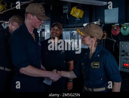 GOLFO ARABICO (16 marzo 2022) CMdR. Meghan Bodnar, destra, ufficiale comandante, scuote le mani con il tecnico dei sistemi informativi Seaman Jacob Roof durante una cerimonia di premiazione del Guerriero della settimana a bordo del cacciatorpediniere di missili guidati USS Gridley (DDG 101) nel Golfo Arabico, marzo 16. Gridley è schierato nell'area delle operazioni della flotta degli Stati Uniti 5th a sostegno delle operazioni navali per assicurare la stabilità e la sicurezza marittima nella regione centrale, collegando il Mediterraneo e il Pacifico attraverso l'Oceano Indiano occidentale e tre punti di arresto strategici. Foto Stock