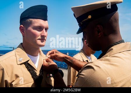 MARE DELLE FILIPPINE (16 marzo 2022) il capo Boatswain Mate Rod Lee, a destra, di Los Angeles, colloca i dispositivi da collare sulla classe Boatswain Mate 1st Brandon Ross, a sinistra, di Anderson, S.C., durante una meritoria cerimonia di promozione sul precipizio del cacciatorpediniere missilistico guidato di classe Arleigh Burke USS Spruance (DDG 111). Abraham Lincoln Strike Group è in fase di implementazione pianificata nell'area delle operazioni della flotta 7th degli Stati Uniti per migliorare l'interoperabilità attraverso alleanze e partnership e al tempo stesso fungere da forza di risposta pronta a sostegno di una regione indomPacifico libera e aperta. Foto Stock