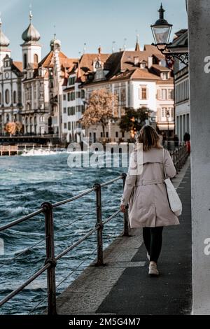 Una foto verticale di una donna che cammina a Lucerna con la Chiesa gesuita sullo sfondo, la Svizzera Foto Stock