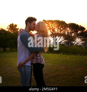 Cant ottenere abbastanza dei vostri baci. una giovane coppia affettuosa che condivide un bacio al tramonto. Foto Stock