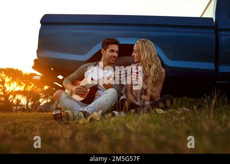 Canzoni d'amore e romanticismo. un giovane che suona la chitarra per la sua ragazza in viaggio. Foto Stock