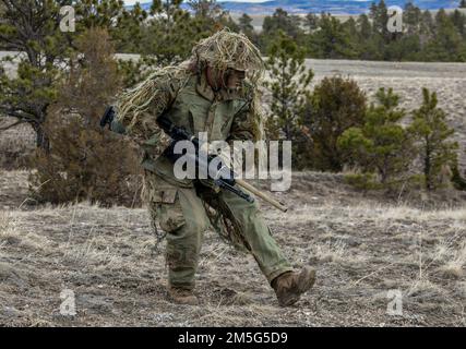 Personale Aaron Lee, 341 Missile Security Operations Squadron, Malmstrom Air Force base, Montana, dimostra i diversi tipi di striscioni che un cecchino farà per rimanere nascosto 16 marzo 2022 a Camp Guernsey, Wyoming. Lee stava dimostrando ai leader difensori del Regional Training Center Workshop che sono venuti a vedere gli Airmen partecipare al corso Nuclear Advanced Designated Marksman. Foto Stock