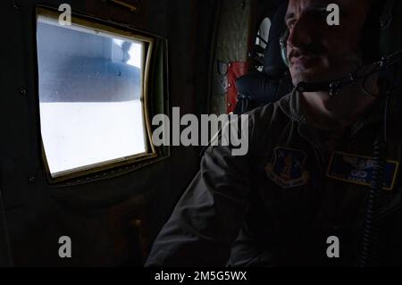 Tecnologia Air Force. SGT. Radek Kret, un maestro di carico assegnato alla 103rd Airlift Wing, coetanei attraverso una porta paracadutismo durante una missione di addestramento a bordo di un aereo C-130H, 17 marzo 2022, East Granby, Conn I Loadmaster monitorano l'aeromobile, eseguono la scansione delle minacce e sono responsabili del corretto caricamento e del fissaggio del carico per rilevare eventuali gocce d'aria. Foto Stock