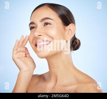 Viso, bellezza e cura della pelle con una modella in studio su sfondo blu per un trattamento sano. Pensare, viso e benessere con un attraente Foto Stock