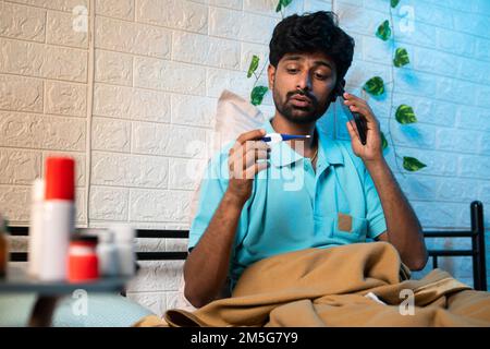 Uomo malato che chiama il medico dopo aver visto la temperatura a causa della febbre di notte - tele concetto assistenza sanitaria, Medicare e trattamento Foto Stock