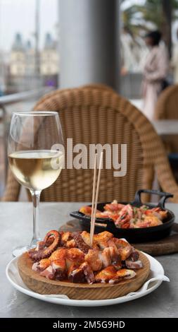 Pranzo a base di pesce e vino bianco in un bar di strada. Piatti appetitosi sul tavolo. Foto Stock