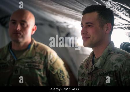 Lo staff Brendan Smith, un difensore dell'aria assegnato al battaglione del 5th, 7th reggimento dell'artiglieria di difesa aerea, riceve la moneta del comandante per l'eccellenza dal generale Greg Brady, comandante generale del comando della difesa aerea e missilistica dell'esercito del 10th durante una visita in Polonia il 16 marzo 2022. Foto Stock