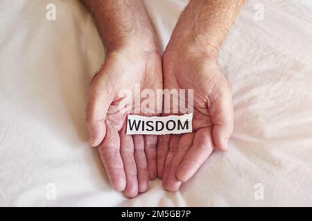 Il più grande tutor che i giovani hanno è l'esperienza. una persona che tiene un pezzo di carta con la parola saggezza scritta su di esso. Foto Stock