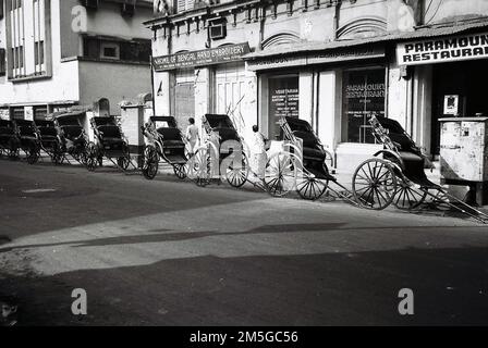 Novembre 1991, Kolkata, India. Risciò parcheggiato in una lunga fila su Mirza Ghalib St Foto Stock