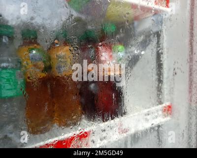 Foto sfocata o sfocata di bottiglie di bevande di marca famosa in frigorifero di vetro nel supermercato Foto Stock