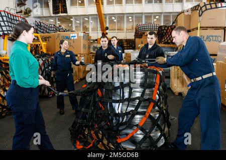 MARE DELLE FILIPPINE (17 marzo 2022) i marinai preparano il carico per uno scarico nella baia di hangar a bordo della portaerei di classe Nimitz USS Abraham Lincoln (CVN 72). Abraham Lincoln Strike Group è in fase di implementazione pianificata nell'area delle operazioni della flotta 7th degli Stati Uniti per migliorare l'interoperabilità attraverso alleanze e partnership e al tempo stesso fungere da forza di risposta pronta a sostegno di una regione indomPacifico libera e aperta. Foto Stock