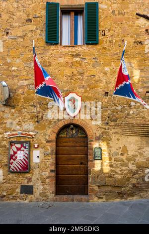 Porta di un antico edificio con bandiere e poster pubblicitari, Montisi, Provincia di Siena, Regione Toscana, Italia Foto Stock