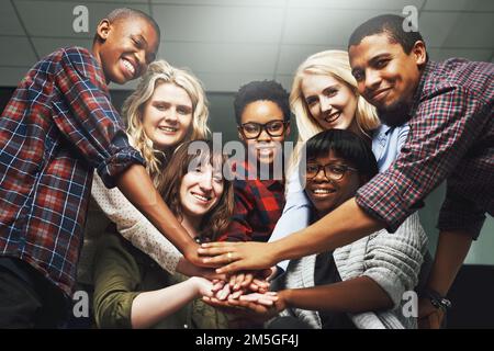 Come team siamo più forti. un gruppo di allegri colleghi di lavoro che formano insieme un huddle. Foto Stock