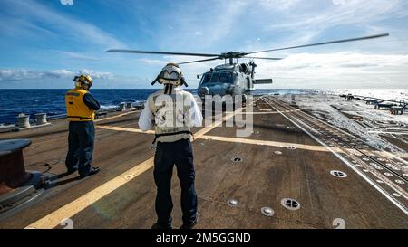 MARE DELLE FILIPPINE (17 marzo 2022) Boatswain’s Mate 2nd Class Jewlian Wilson, a sinistra, da Jacksonville, Florida, E Boatswain’s Mate 2nd Class Scott Wright, di Sylvania, Ala., guarda come un elicottero MH-60R Sea Hawk, assegnato ai “Raptors” dell’elicottero Maritime Strike Squadron (HSM) 71, si prepara a lanciare dal ponte di volo del cacciatorpediniere missilistico guidato di classe Arleigh Burke USS Spruance (DDG 111). Abraham Lincoln Strike Group è in fase di implementazione pianificata nell'area delle operazioni della flotta 7th degli Stati Uniti per migliorare l'interoperabilità attraverso alleanze e partnership e al tempo stesso servire da pronta risposta Foto Stock