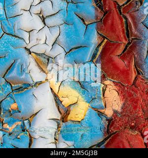 Vernice da peeling rossa, bianca e blu su una vecchia parete Foto Stock
